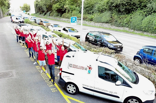 Das Team der MCG Sockelleisten AG versammelt neben einer Reihe von Fahrzeugen.